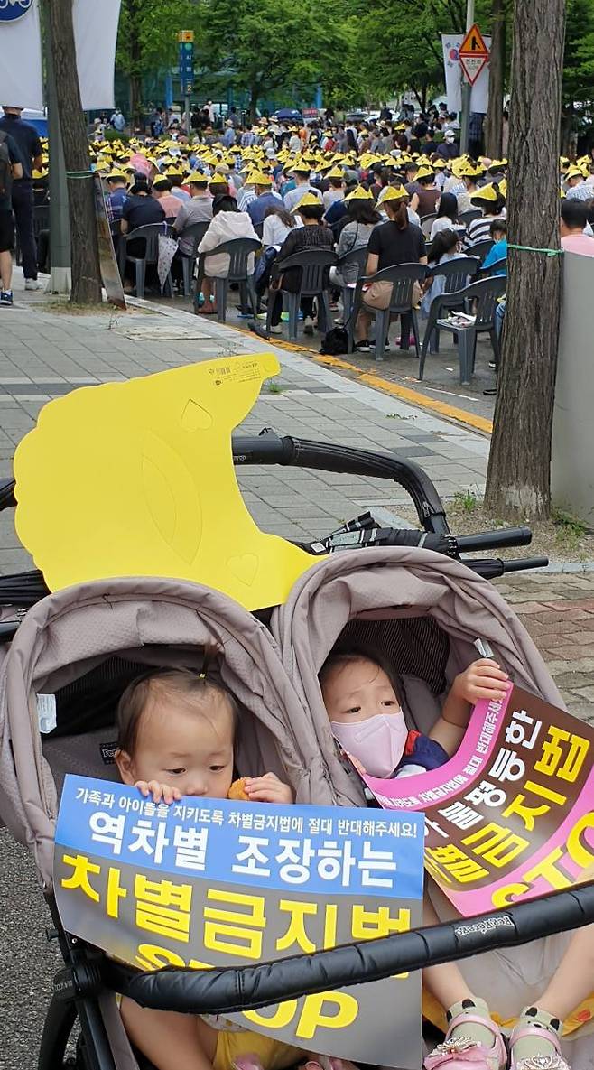 대회가 열리는 도로 옆 인도에 멈춰선 탈것 안의 어린아이 두명이 이날 대회 구호가 적힌 표지판을 들고 있어 눈길을 끈다.