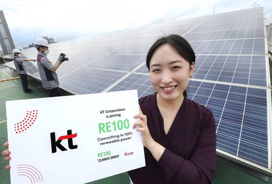 A KT employee poses for a photo in front of solar panels installed at the company's office building in Gwanak District, southern Seoul. [KT]