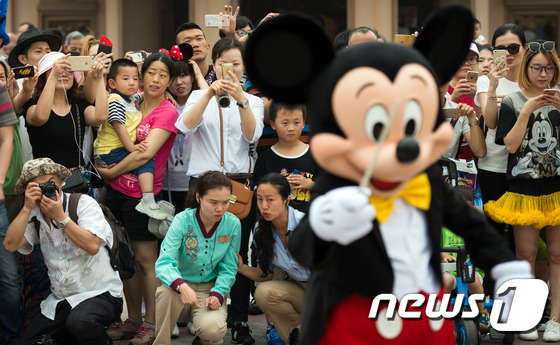 상하이 디즈니랜드에서 사람들이 퍼레이드를 진행중인 미키마우스 사진을 찍고 있다. © AFP=뉴스1