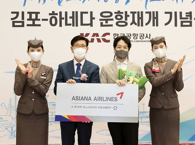 ◇아시아나항공이 29일 김포공항 국제선 청사에서 한국공항공사와 함께 김포-하네다 노선 재운항 기념식을 가졌다. 정성권 아시아나항공 대표(왼쪽 두번째)가 출발편 탑승객 1명에게 김포-하네다 노선 왕복 항공권을 증정한 후 기념촬영을 하고 있는 모습.