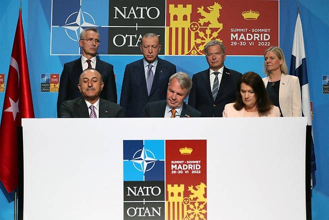 28일(현지시간) 스페인 마드리드에서 (뒷줄 왼쪽부터) 옌스 스톨텐베르그 북대서양조약기구(NATO·나토) 사무총장, 레제프 타이이프 에르도안 튀르키예(터키) 대통령, 사울리 니니스토 핀란드 대통령, 막달레나 안데르손 스웨덴 총리가  (앞에서 왼쪽부터)  메블뤼트 차우쇼을루 튀르키예 외무장관,  페카 하비스토 핀란드 외무장관, 안 린데 스웨덴 외무장관이 '스웨덴·핀란드 나토 가입 지지' 관련 양해 각서에 서명하는 보습을 지켜보고 있다. /AFPBBNews=뉴스1