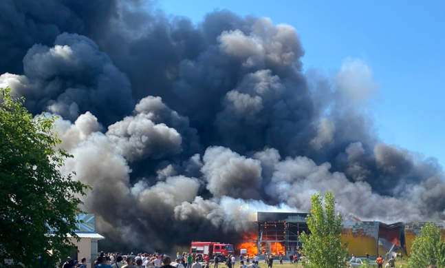 27일(현지시간) 우크라이나 크레멘추크에서 시민들이 러시아의 미사일 공격으로 연기가 솟구치는 쇼핑몰을 지켜보고 있다. 우크라이나 당국은 이번 공격으로 최소 13명이 숨지고 58명이 다쳤다고 밝혔다. 크레멘추크=AP뉴시스