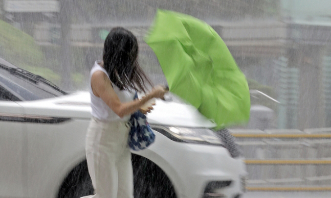 국지성 호우가 쏟아진 지난 28일 오후 서울시 중구 을지로1가사거리인근에서 한 시민이 비바람에 고장 난 우산을 들고 이동하고 있다. 뉴시스