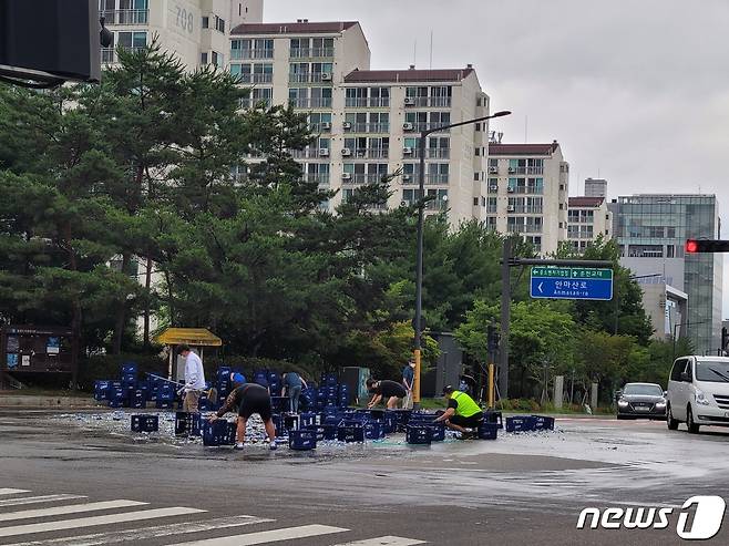 지난 29일 춘천시 퇴계동의 한 사거리에서 5톤 트럭에 실려있던 맥주병 2000여병이 바닥으로 떨어지는 사고가 발생, 길을 가던 시민들이 청소를 돕고 있다.(독자 제공)© 뉴스1