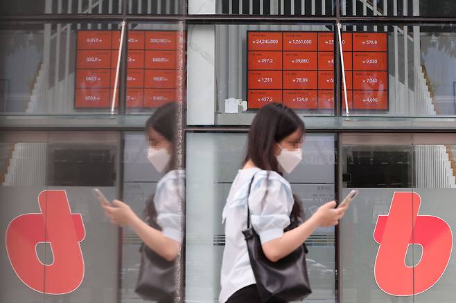지난 19일 시세 전광판이 설치된 서울 서초구 빗썸 고객센터 앞을 한 시민이 지나가고 있다. /연합뉴스