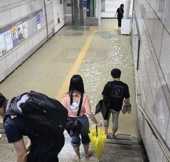 30일 오전 호우특보가 발령된 가운데, 수원시 권선구 1호선 전철 세류역 지하통로가 침수돼 출근길 시민들이 신발을 벗은 채로 걸어가고 있다. [트위터 캡처]