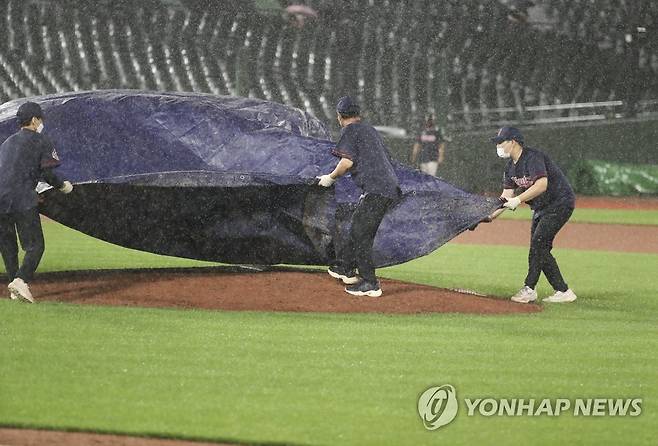 부산 사직구장 폭우로 경기 중단 (부산=연합뉴스) 강덕철 기자 = 28일 부산 사직야구장에서 열린 프로야구 두산 베어스와 롯데 자이언츠의 경기. 8회 초 폭우가 내리자 롯데구단 관계자가 방수포를 덮고 있다. 2022.6.28 kangdcc@yna.co.kr