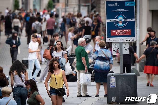 지난해 6월 17일(현지시간) 야외 마스크 의무 착용이 해제된 첫날 프랑스 낭트 거리에 아직 남아있는 마스크 착용 안내판 옆을 마스크를 안 쓴 시민들이 걸어가고 있다. © AFP=뉴스1 © News1 우동명 기자