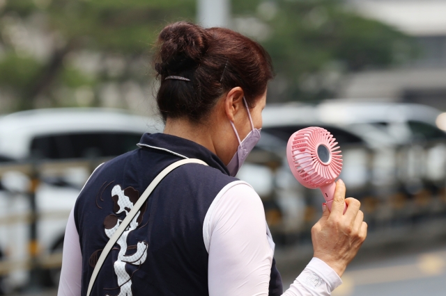 폭염이 이어진 4일 오후 서울 서초구 신반포로에서 한 시민이 손풍기를 들고 이동하고 있다. 연합뉴스
