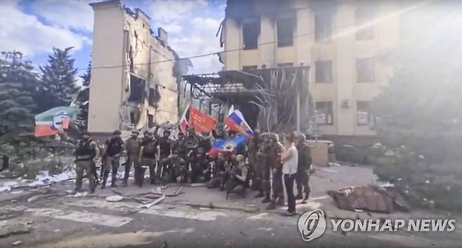 파괴된 리시찬스크 건물 앞서 기념촬영하는 러시아군 병사들 [AP 연합뉴스자료사진. 재판매 및 DB 금지]