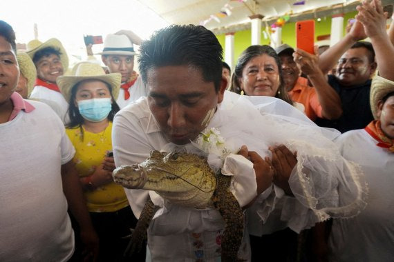 The San Pedro Huamelula Mayor Victor Hugo Sosa kisses a seven-year-old alligator dressed as a bride during a traditional ritual marriage, likely dates back centuries to pre-Hispanic times, between the mayor and the reptile that depicts a princess, as a prayer to plead for nature's bounty, in San Pedro Huamelula, in Oaxaca state, Mexico June 30, 2022. /사진=뉴스1 외신화상