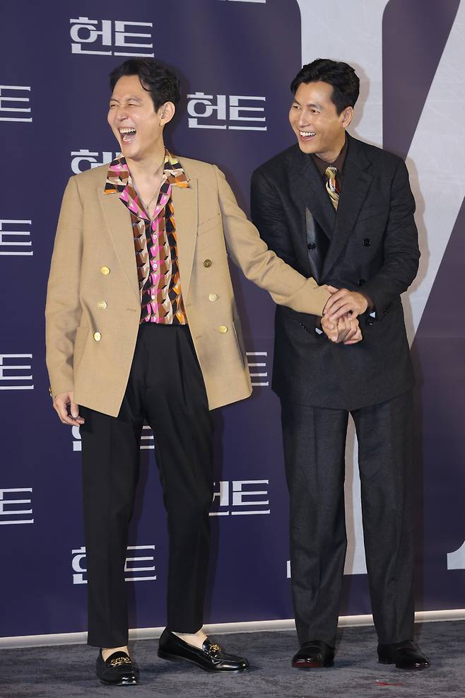 Lee Jung-jae (left) and Jung Woo-sung hold hands during a photo session after a press conference introducing “Hunt” at Megabox Seongsu in Seoul, Tuesday. (Yonhap)