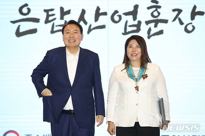 [서울=뉴시스] 전신 기자 = 윤석열 대통령이 5일 서울 여의도 중소기업중앙회관에서 열린 제1회 여성기업주간 개막식에서 윤공순 ㈜구구플라워 대표이사에게 은탑산업훈장을 수여한 후 기념촬영을 하고 있다. 2022.07.05. photo1006@newsis.com