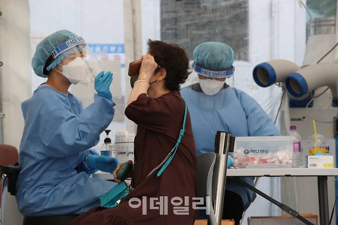 [이데일리 이영훈 기자] 무더위가 계속된 6일 서울 양천구보건소 선별진료소에서 관계자가 PCR 검사를 하고 있다.