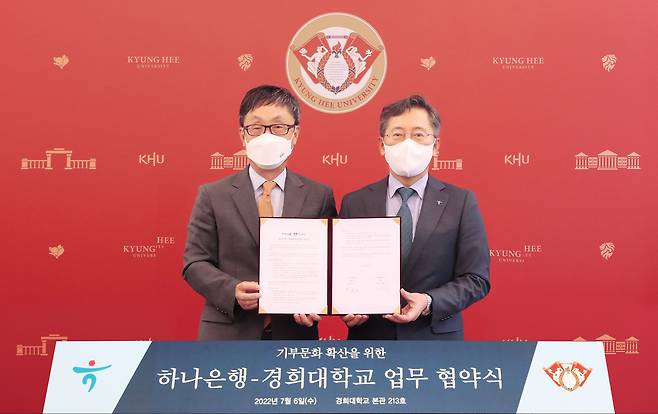 Kyung Hee University President Hahn Kyun-tae (left) and Hana Bank CEO Park Sung-ho sign an agreement on launching a philanthropic campaign to have people give away their wealth to charity after death, at the university headquarters in Seoul on Wednesday. (Hana Bank)