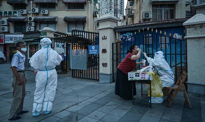 지난 5일(현지시간) 중국 상하이 징안(京安)구의 한 주택가 옆 거리에서 코로나바이러스 검사를 위해 한 여성의 검체를 채취하고 있다. AFP연합뉴스