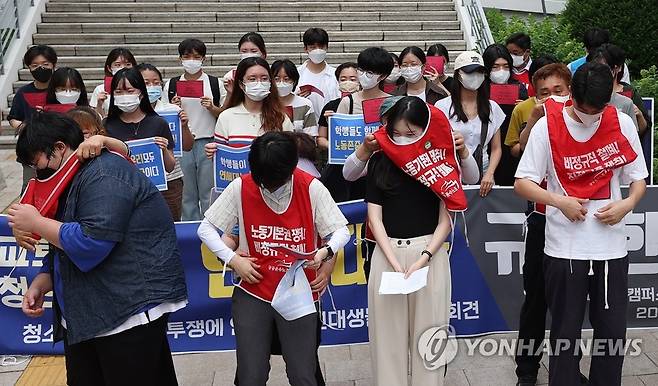 빨간조끼 수여식 (서울=연합뉴스) 신현우 기자 = 6일 오전 서울 서대문구 연세대학교 백양관 앞에서 열린 청소경비 노동자 투쟁에 연대하는 연대생 기자회견에서 노동자들이 학생들에게 조끼를 입혀주는 퍼포먼스를 하고 있다. 2022.7.6 nowwego@yna.co.kr