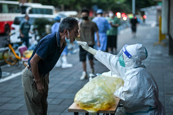 중국 상하이 징안구에서 보건요원이 한 남성의 코로나19 검사를 하며 검체를 채취하고 있다. 2022.7.5 AFP 연합뉴스