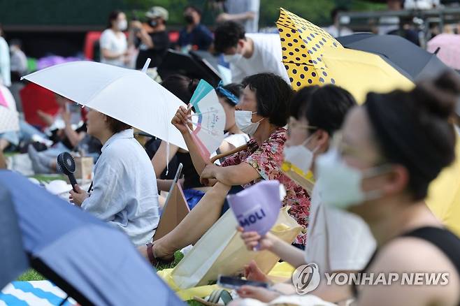 무더위 뚫고 콘서트로 (서울=연합뉴스) 임화영 기자 = 무더운 날씨를 보인 7일 오후 서울 시청광장에서 열린 '참신한 북 콘서트'에서 관람객들이 우산을 쓴 채 부채질을 하고 있다. 2022.7.7 hwayoung7@yna.co.kr