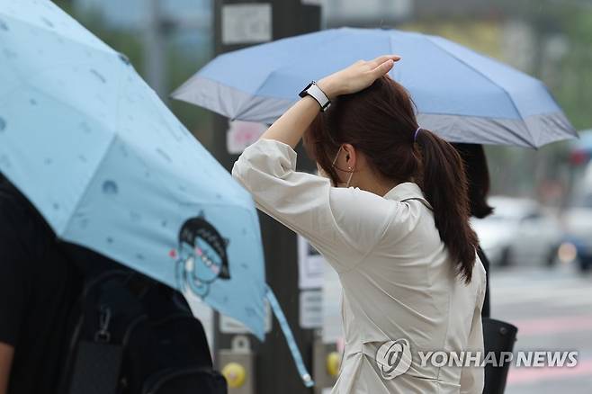 한 시민이 손으로 비를 막으며 발걸음을 재촉하고 있다. [연합뉴스 자료사진]