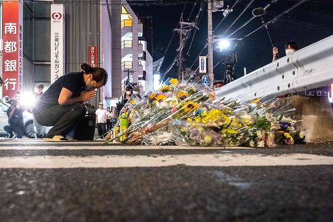 아베 전 총리가 피격당한 장소에 놓인 조화 앞에서 기도하고 있는 한 시민. AFP=연합뉴스