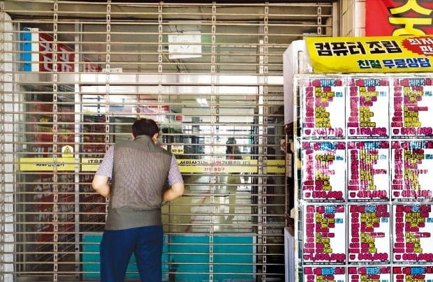 < 결국 못 버티고… > 3일 서울 용산구 선인상가 앞에서 한 시민이 문 닫힌 조립 PC 상가 안을 들여다보고 있다. 인근 부동산중개업소에 따르면 최근 두 달 동안에만 이곳 상인들이 내놓은 점포가 30개를 넘었다. 김병언 기자
