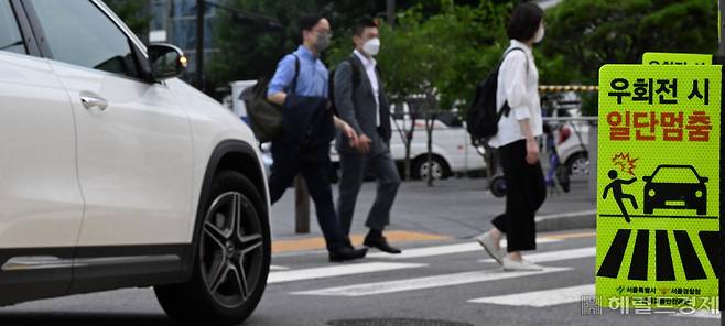 횡단보도 앞 일시 정지 의무 확대 내용이 담긴 도로교통법 개정안 시행일인 12일 서울 용산구의 한 교차로에서 시민들이 횡단보도를 건너고 있는 가운데 일시멈춤 안내판이 설치되어 있다. 임세준 기자