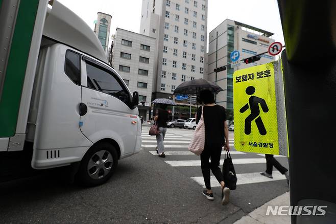 [서울=뉴시스] 백동현 기자 = 횡단보도 앞 일시정지 의무를 확대하는 등 보행자 보호의무가 강화된 도로교통법 시행 첫날인 12일 오후 서울 시내 한 횡단보도 옆에 '보행자 보호' 안내문이 부착돼 있다. 2022.07.12. livertrent@newsis.com