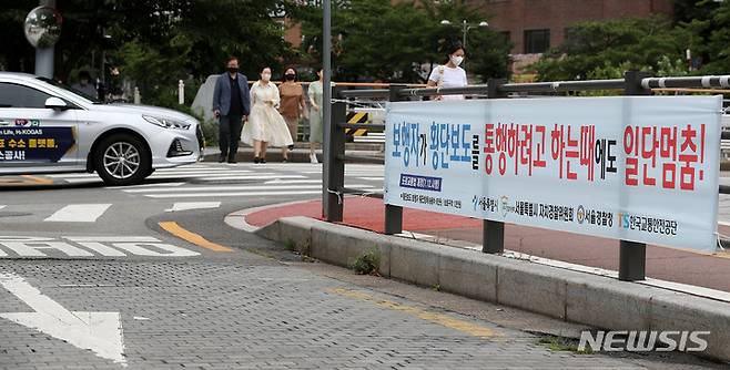 [서울=뉴시스] 백동현 기자 = 횡단보도 앞 일시정지 의무를 확대하는 등 보행자 보호의무가 강화된 도로교통법 시행 첫날인 12일 오후 서울 시내 한 신호등 없는 횡단보도에서 차량이 보행자의 횡단을 기다리지 않고 주행하고 있다. 2022.07.12. livertrent@newsis.com