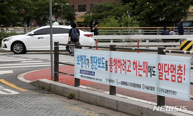 [서울=뉴시스] 백동현 기자 = 횡단보도 앞 일시정지 의무를 확대하는 등 보행자 보호의무가 강화된 도로교통법 시행 첫날인 12일 오후 서울 시내 한 신호등 없는 횡단보도에서 차량이 보행자의 횡단을 기다리지 않고 주행하고 있다. 2022.07.12. livertrent@newsis.com