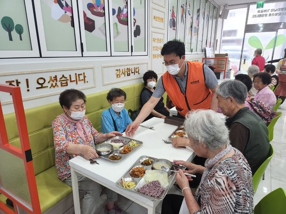 강정칠 부산연탄은행 대표가 노인들의 식탁에 급식판을 내려놓고 있다