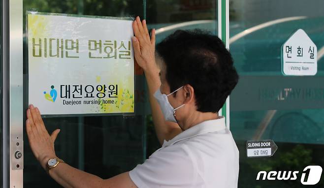 방역당국이 요양병원·시설 접촉 면회를 금지하고 병상확보 행정명령을 발동하는 등 신종 코로나바이러스 감염증(코로나19) 6차 대유행에 대비한 방역대책을 발표한 20일 오후 대전 서구 대전요양원에서 직원이 비접촉면회실 안내 문구를 붙이고 있다. 이번 방역대책은 요양병원·시설, 정신병원·시설의 모든 종사자를 대상으로 주 1회 PCR 검사를 실시하고 비접촉 면회만 허용된다. 2022.7.20/뉴스1 © News1 김기태 기자