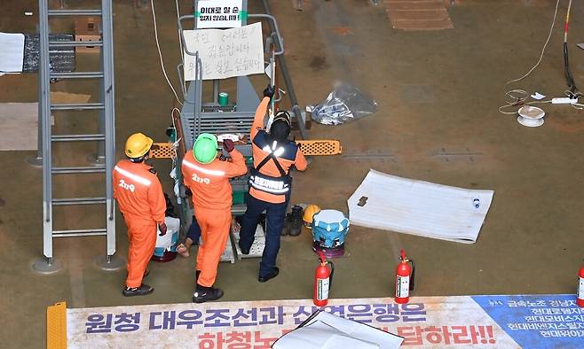 대우조선해양 하청 노사협상이 극적으로 타결된 지난 22일 오후 경남 거제시 아주동 대우조선해양 옥포조선소 내 1독에서 대우조선 소방대원이 철 구조물에서 농성 중인 유최안 금속노조 거제통영고성 조선하청지회 부지회장을 살펴보고 있다. 공동취재사진