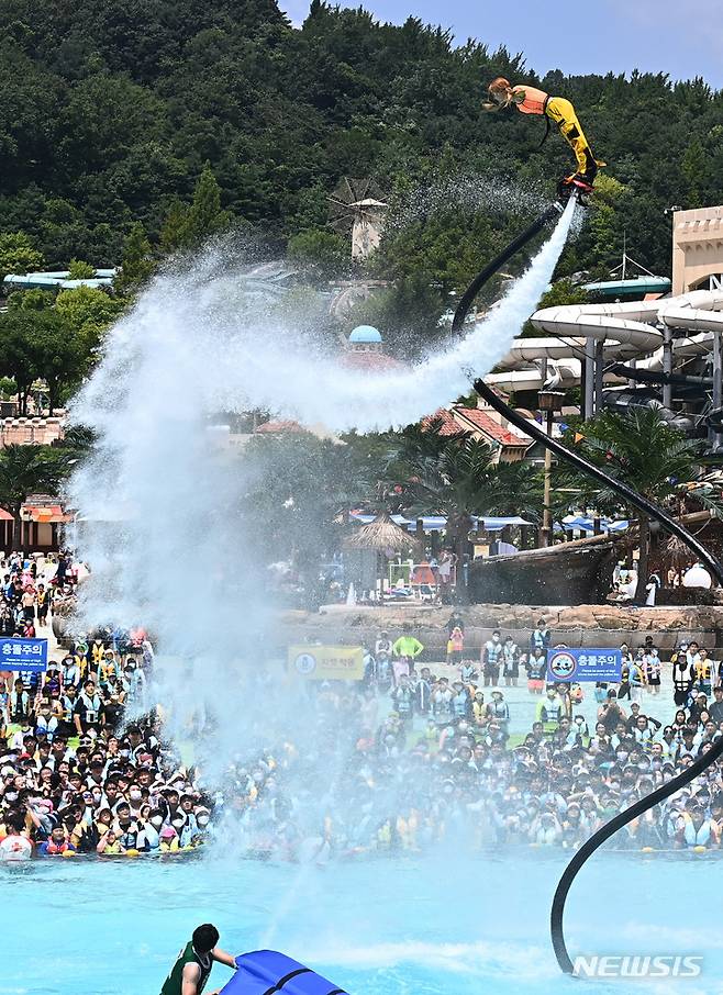 [용인=뉴시스] 김종택기자 = 전국 대부분 지역에 폭염주의보가 내려진 25일 오후 경기도 용인 캐리비안베이를 찾은 시민들이 시원한 물줄기를 뿜으며 하늘을 나는 플라이보드쇼를 보며 더위를 식히고 있다. 2022.07.25. jtk@newsis.com