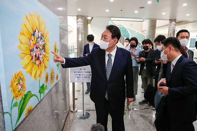 윤석열 대통령이 25일 오전 용산 대통령실에서 열린 출근길 약식 기자회견(도어스테핑)을 마친 뒤 로비에 새로 걸린 강선아 작가의 '해바라기II' 그림을 둘러보고 있다. 대통령실사진기자단