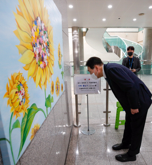 윤석열 대통령이 25일 오전 용산 대통령실에서 열린 출근길 약식 기자회견(도어스테핑)을 마친 뒤 로비에 새로 걸린 강선아 작가의 ‘해바라기II’ 그림을 둘러보고 있다. 2022. 7. 25 박지환 기자