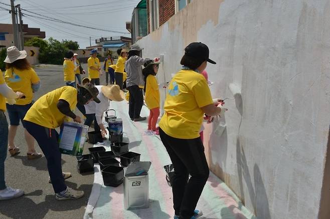 경북 포항시 남구 호미곶면 강사1리 다무포 고래마을에서 주민과 자원봉사자가 담을 하얀색 페인트로 칠하고 있다. 시와 마을협의회는 8월까지 다무포 마을 전체를 하얀색으로 칠할 예정이다. 포항시 제공.