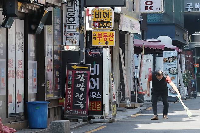 서울 종로구 먹자골목에서 한 업주가 가게 앞을 청소하고 있다./뉴스1