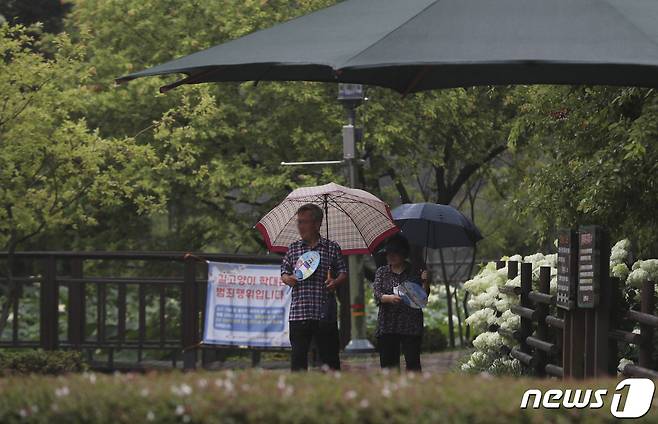 울산지역에 비가 내린 28일 오전 울산 남구 선암호수공원에서 우산을 쓴 시민들이 부채질을 하고 있다. 2022.7.28/뉴스1 ⓒ News1 윤일지 기자