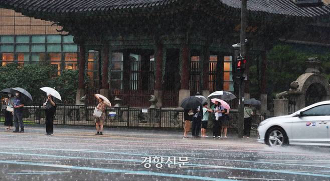 시민들이 장맛비가 내린 지난달 13일 서울 광화문광장 네거리에서 우산을 쓰고 걷고 있다./한수빈 기자