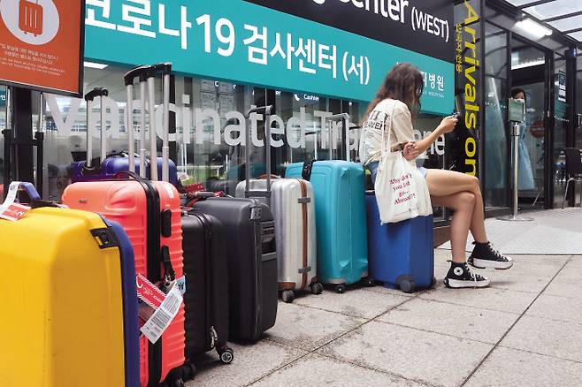 지난 7월 24일 휴가철을 맞은 인천국제공항 제1여객터미널 입국자 신종 코로나바이러스 감염증(코로나19) 검사센터 앞에 검사를 받고 있는 입국자들의 캐리어가 줄지어 놓여 있다. [연합]