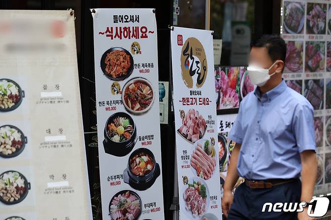 25일 서울 시내 한 거리에서 시민들이 마스크를 착용한 채 식당 메뉴 알림판 앞을 지나고 있다. 2022.7.25/뉴스1 ⓒ News1 조태형 기자