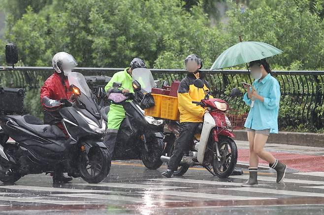비가 내린 지난 7월 점심시간 배달원들이 서울 종로구 종각 젊음의거리 인근에서 배달 중 잠시 정차하고 있다. [연합]
