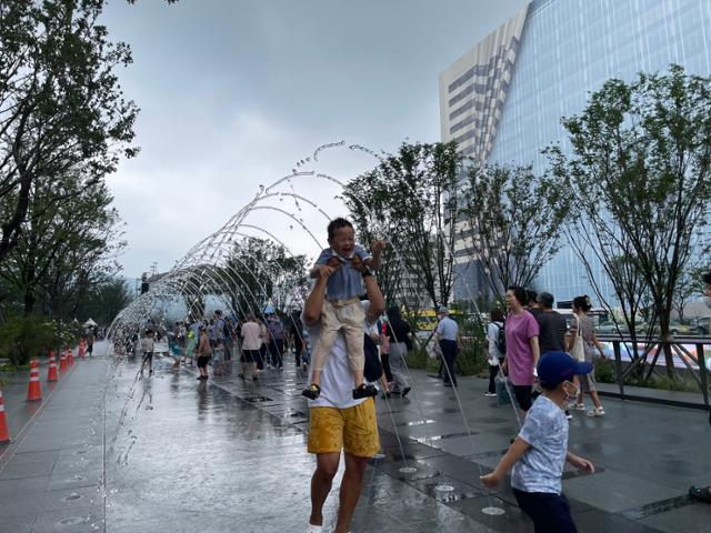 6일 개장한 서울 광화문광장 내 '분수터널'을 한 시민이 아이와 함께 통과하고 있다. 강지원 기자