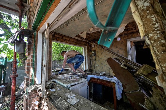 한 민간인 남성이 지난달 20일 우크라이나 드니프로페트로우스크주(州) 니코폴에서 러시아군의 공격으로 파괴된 집의 잔해를 치우고 있다. 로이터=연합뉴스