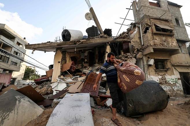 팔레스타인 가자지구의 주민들이 7일(현지시간) 이스라엘의 공습을 받은 뒤 폐허가 된 집에서 가재도구를 옮기고 있다. | AFP연합뉴스