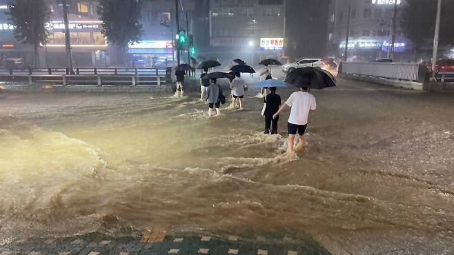 중부지방을 중심으로 폭우가 쏟아진 8일 밤 서울 관악구 도림천이 범람했다. 도림천 주변을 지나는 시민들이 발걸음을 재촉하고 있다. /뉴스1
