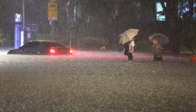 8일 밤 서울 강남구 대치역 인근 도로가 물에 잠기면서 차량과 보행자가 통행하는 데 불편을 겪고 있다.연합뉴스