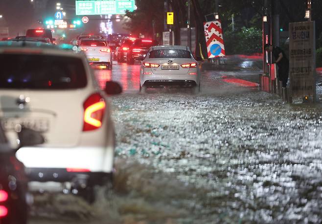 8일 밤 서울 강남구 봉은사역 인근 코엑스 입구에서 관계자들이 인근 도로에 물이 차오르고 있다.  연합뉴스