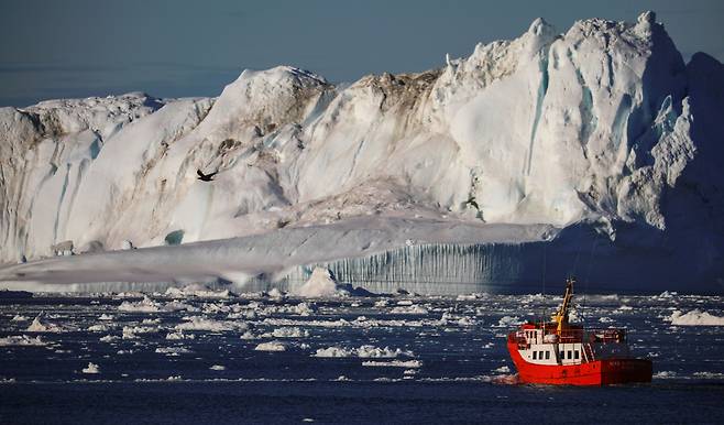 덴마크령 그린란드의 유명 관광지인 일룰리사트 인근 디스코 베이에서 선박 한 척이 거대한 빙산 곁을 지나고 있다.